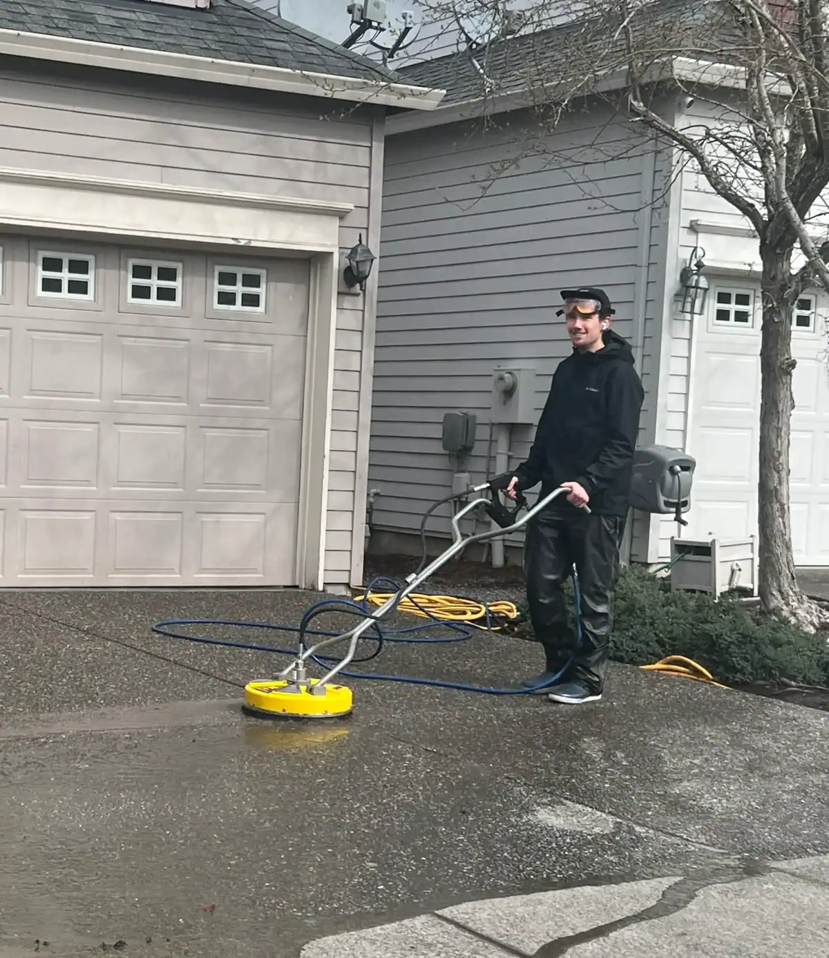 The owner pressure washes a driveway with a circular surface cleaner attachment.