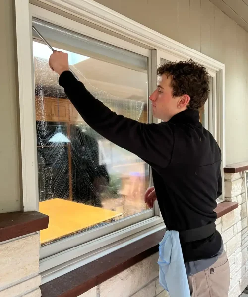 Owner uses squeegee to perform window cleaning.